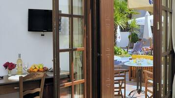 Habitación con comedor, televisión y puerta abierta que da a un espacio exterior con mesa y sillas.