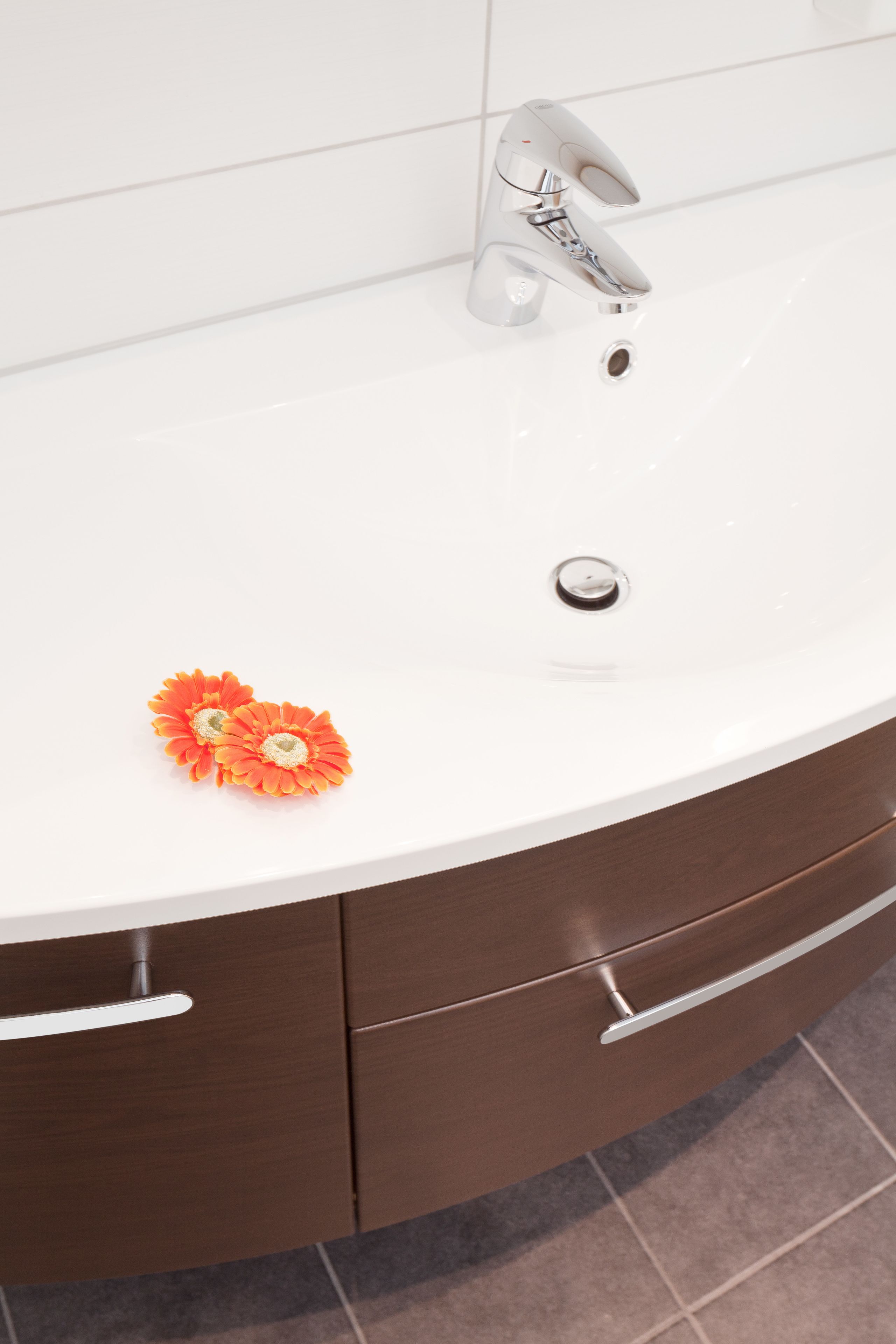 A bathroom with a white sink, a modern faucet, and a wooden vanity.