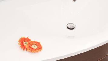 A bathroom with a white sink, a modern faucet, and a wooden vanity.
