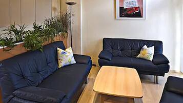 Una sala de estar con dos sofás azul oscuro, una mesa de centro de madera y una planta en maceta.