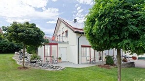 A modern two-story house with a balcony, surrounded by a well-maintained lawn and a small garden area. - Landhotel Garni Engelhard (Kirchheim am Ries)