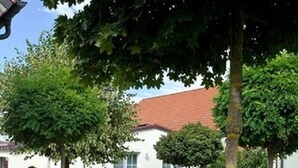 A residential building with a stone fire pit, a well-maintained lawn, and mature trees. - Landhotel Garni Engelhard (Kirchheim am Ries)