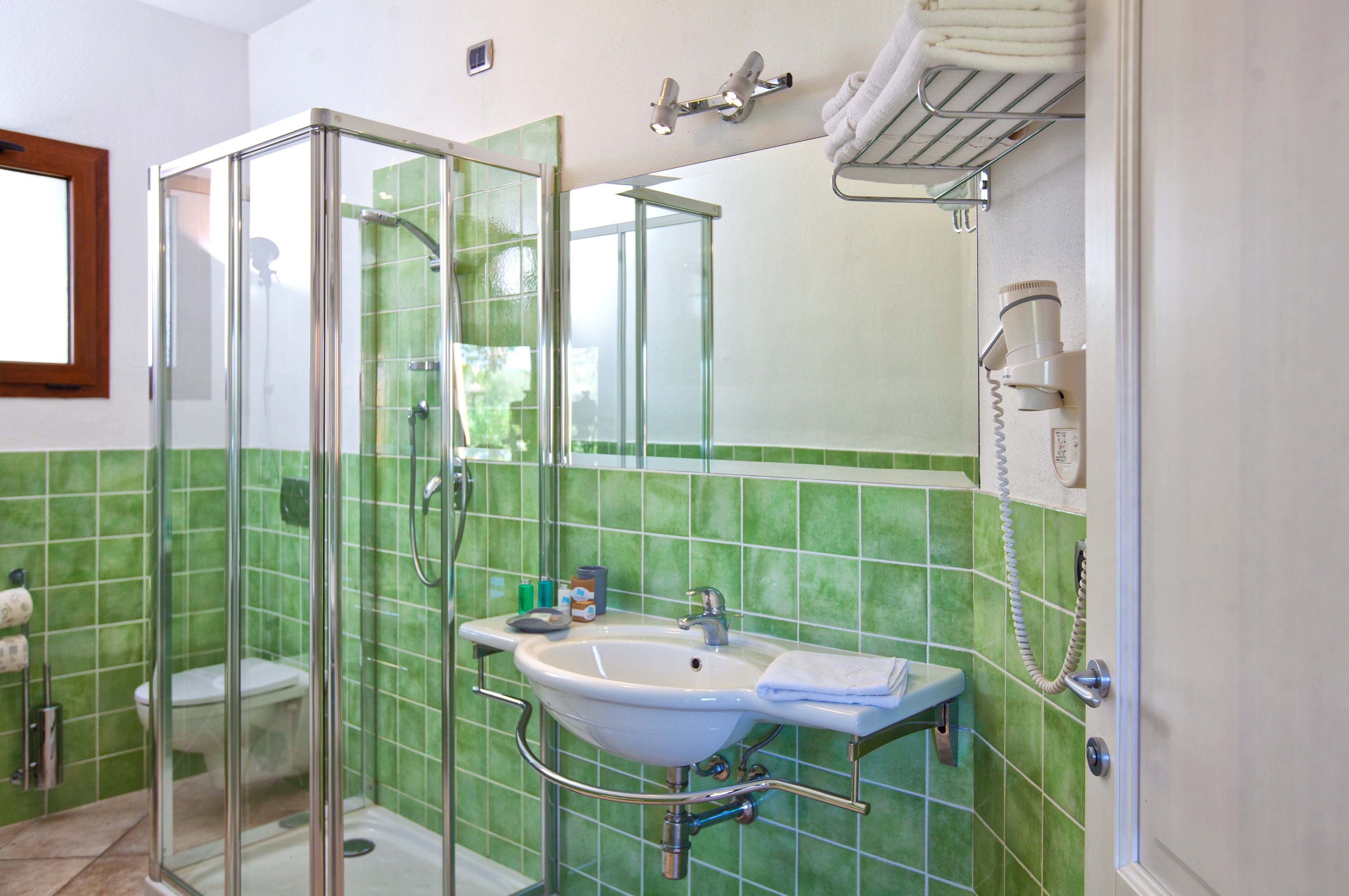 A bathroom with a glass-enclosed shower, a sink with a mirror, and a towel rack.