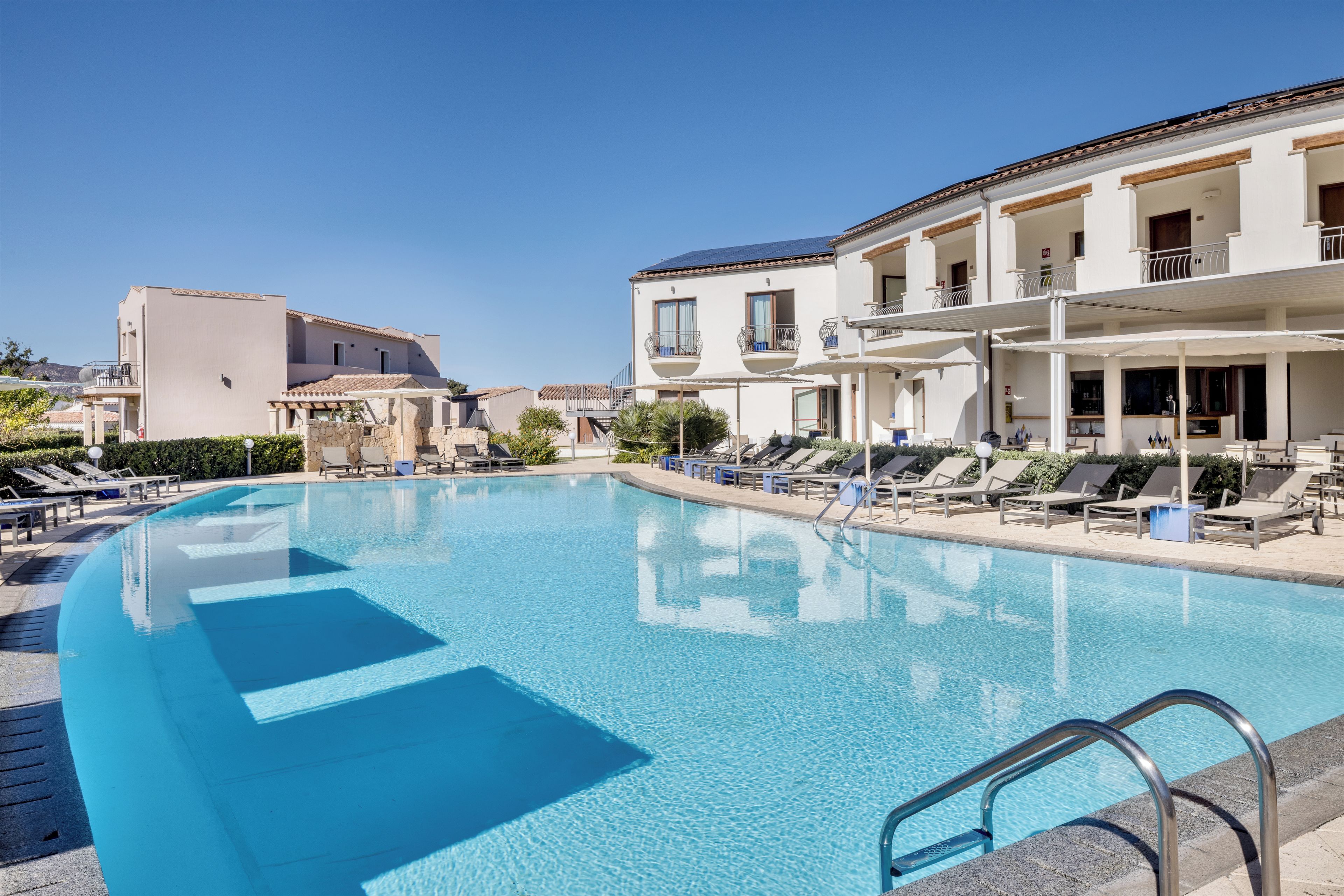 Ein Swimmingpool mit Liegestühlen und einem Gebäude mit Balkonen.