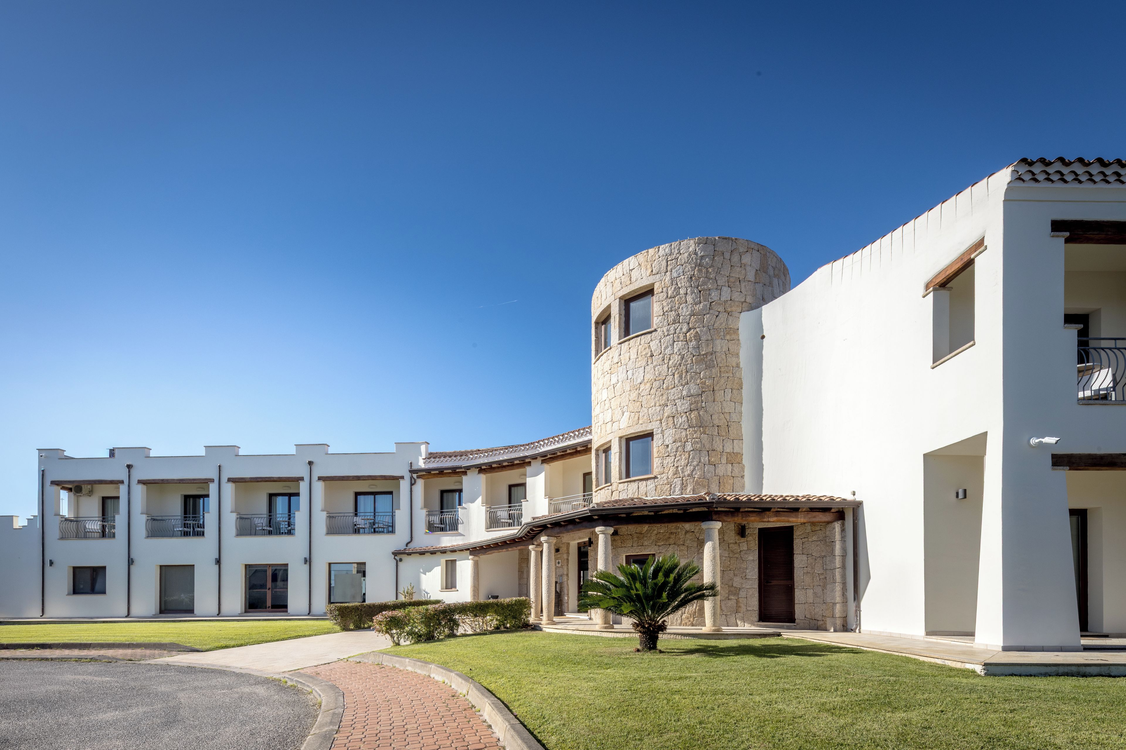 A modern building with a stone tower, multiple balconies, and a well-maintained lawn.