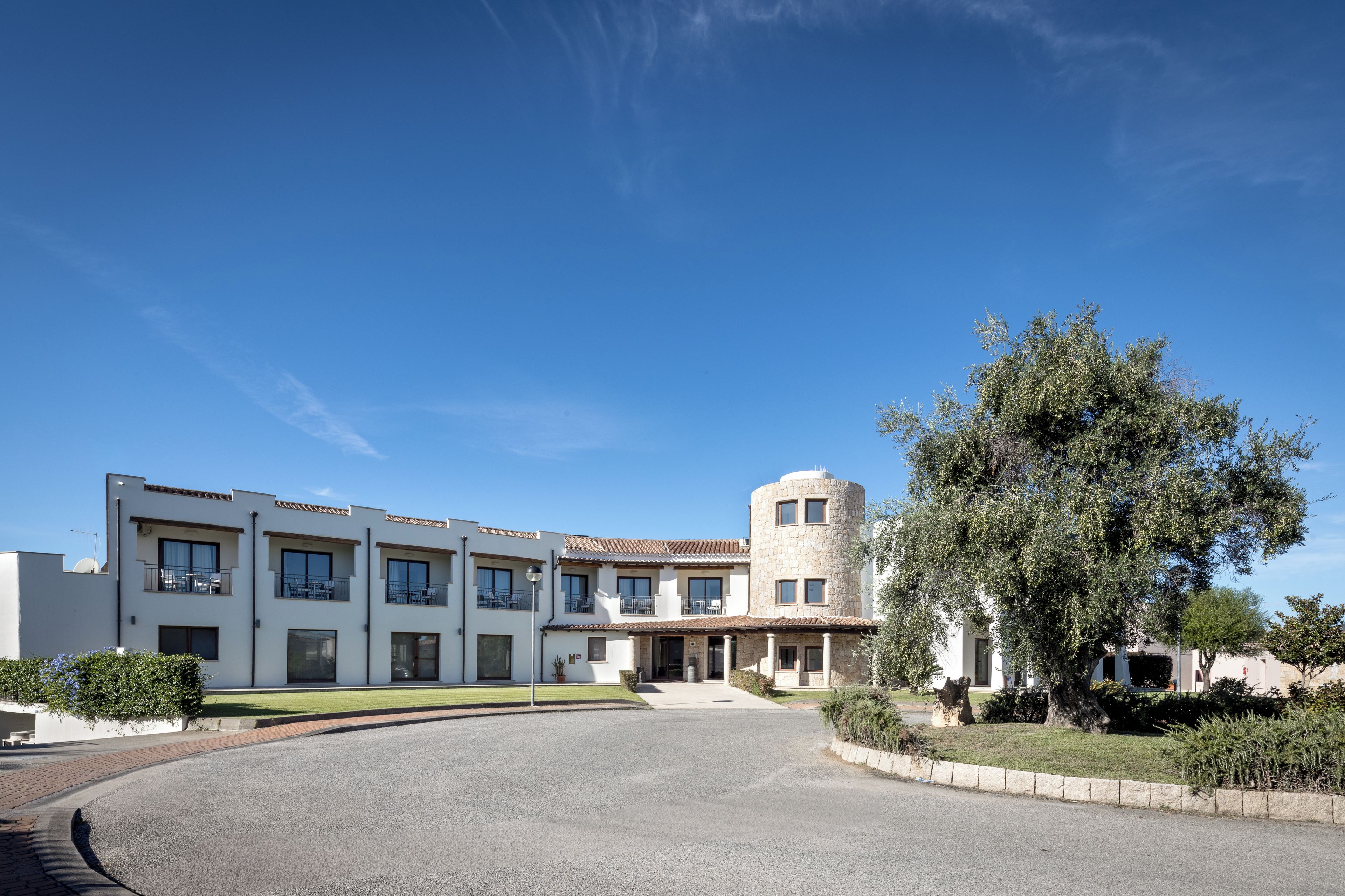 A modern building with a courtyard, a stone tower, and a large tree.