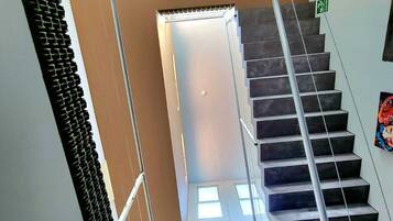 A staircase with a metal railing, a circular skylight, and a green exit sign.
