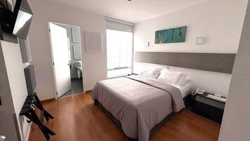 A bedroom with a bed, bedside table, and a desk with a chair.