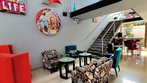 A modern lobby with a staircase, colorful artwork, and a mix of seating options including red chairs and patterned sofas. - Barranco Boutique Hotel by 3B  (Lima)