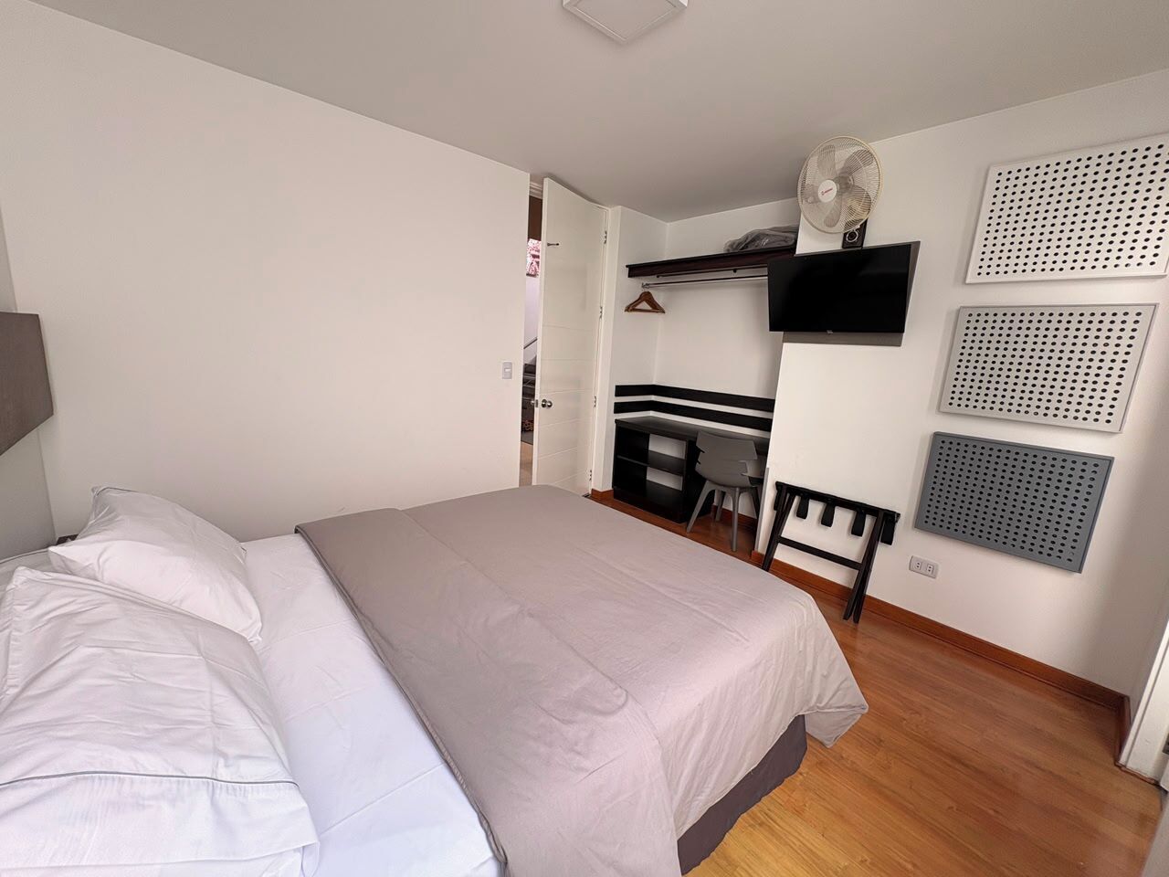 A bedroom with a bed, a desk, and a chair.