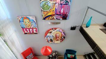 Una sala de estar moderna con un sofá rojo y turquesa, una mesa de centro y un cartel decorativo en la pared.