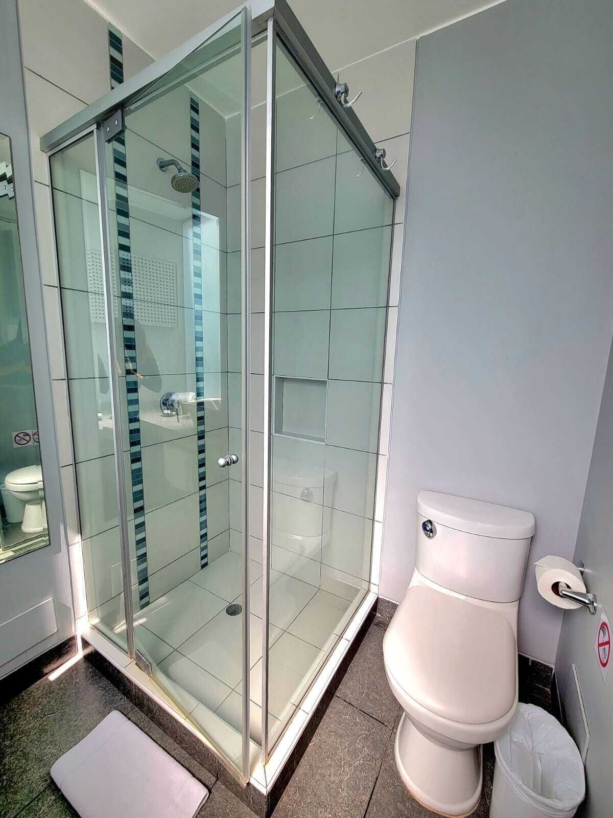 Un baño moderno con ducha envuelta en vidrio, inodoro y bidé.