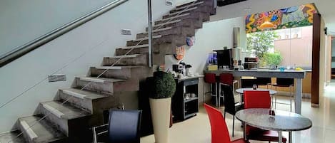 A modern interior with a staircase, dining area, and artwork.
