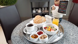 A breakfast tray with croissant, coffee, fruit bowl, juice, and condiments on a granite table. - Barranco Boutique Hotel by 3B  (Lima)