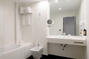 A modern bathroom with a bathtub, a sink, a mirror, and a towel rack. - Hotel Infanta Leonor (Ecija)