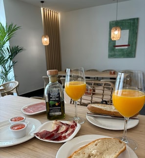 A breakfast setting with plates of food, glasses of orange juice, and a bottle of olive oil. - Hotel Infanta Leonor (Ecija)
