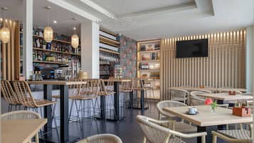 Un área de bar moderna con sillas de mimbre, una barra y estantes llenos de botellas.