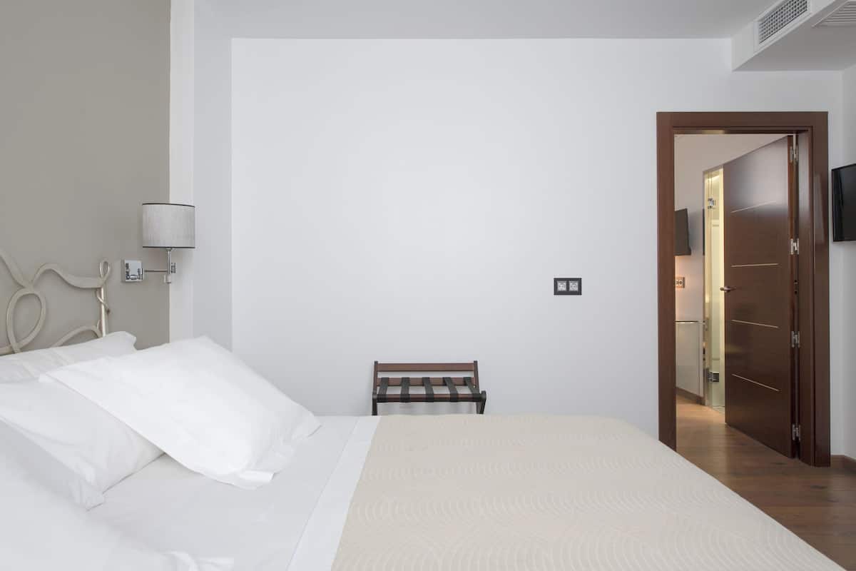 Un dormitorio con cama, mesita de noche, lámpara y armario.