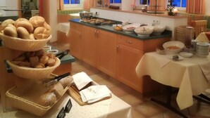 Un buffet de petit-déjeuner avec divers plats et une table recouverte d’une nappe blanche.