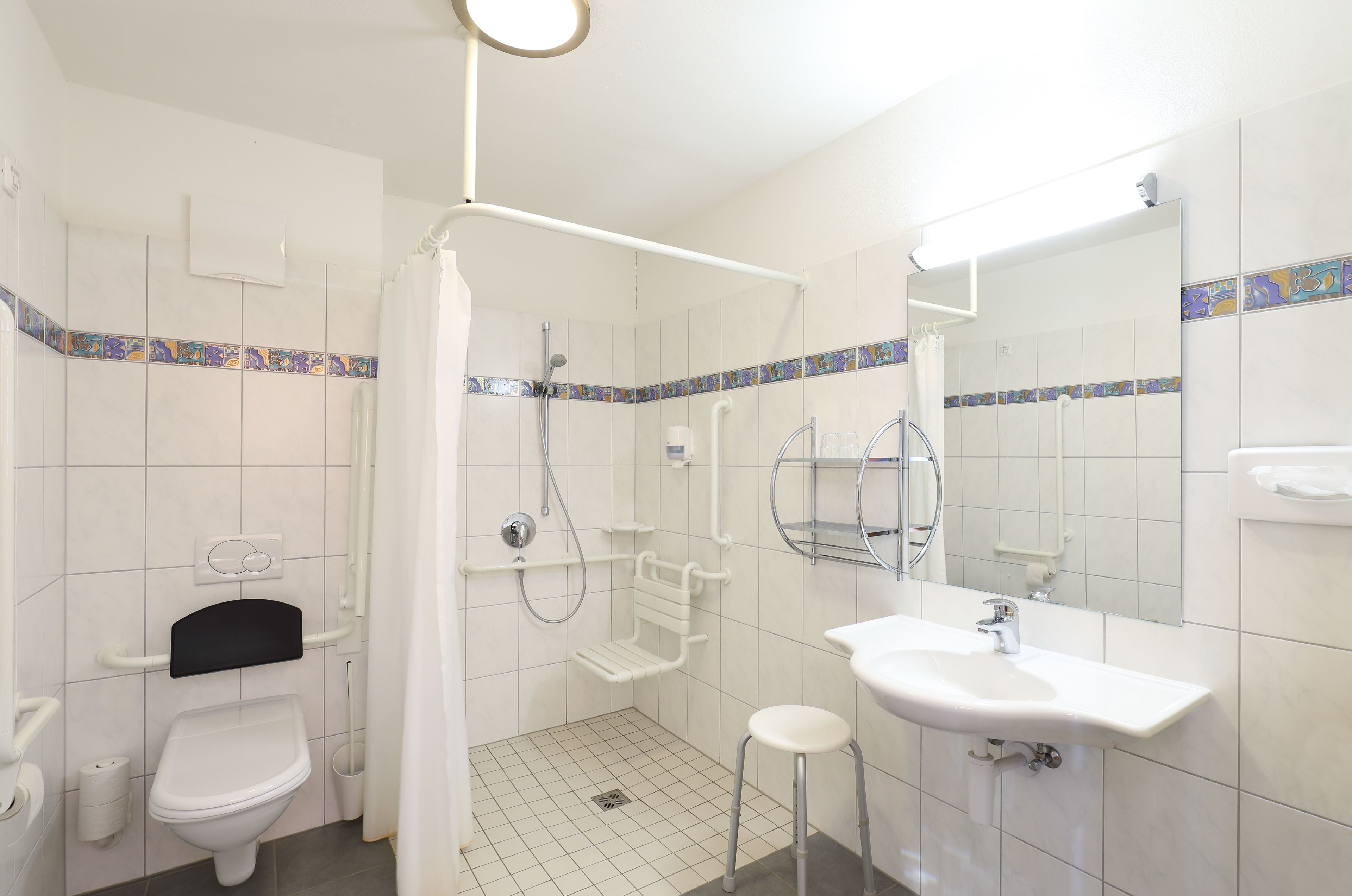 A bathroom with a toilet, shower, and sink.
