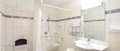 A bathroom with a toilet, shower, and sink.