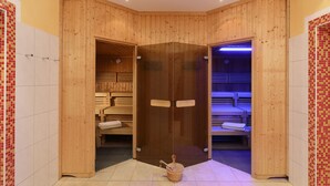 Un sauna avec des murs et des bancs en bois, une porte en verre et un seau contenant une serviette.