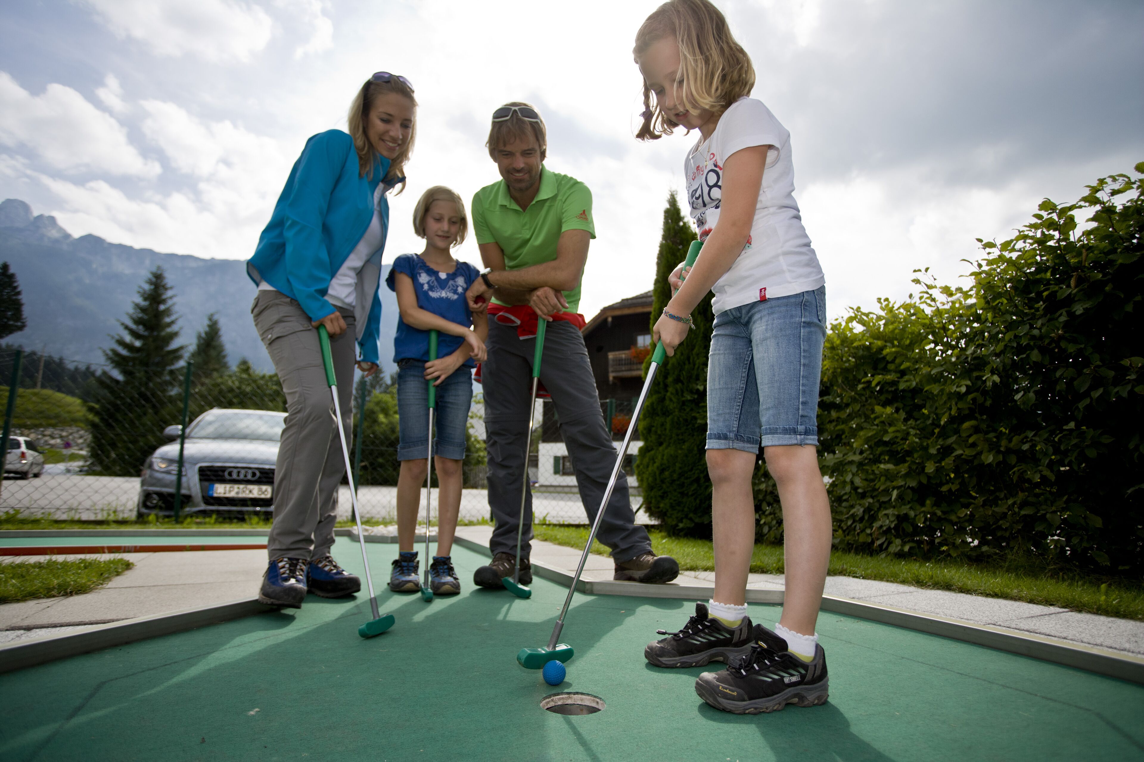 A group of people playing croquet on an outdoor court with a mountain backdrop.