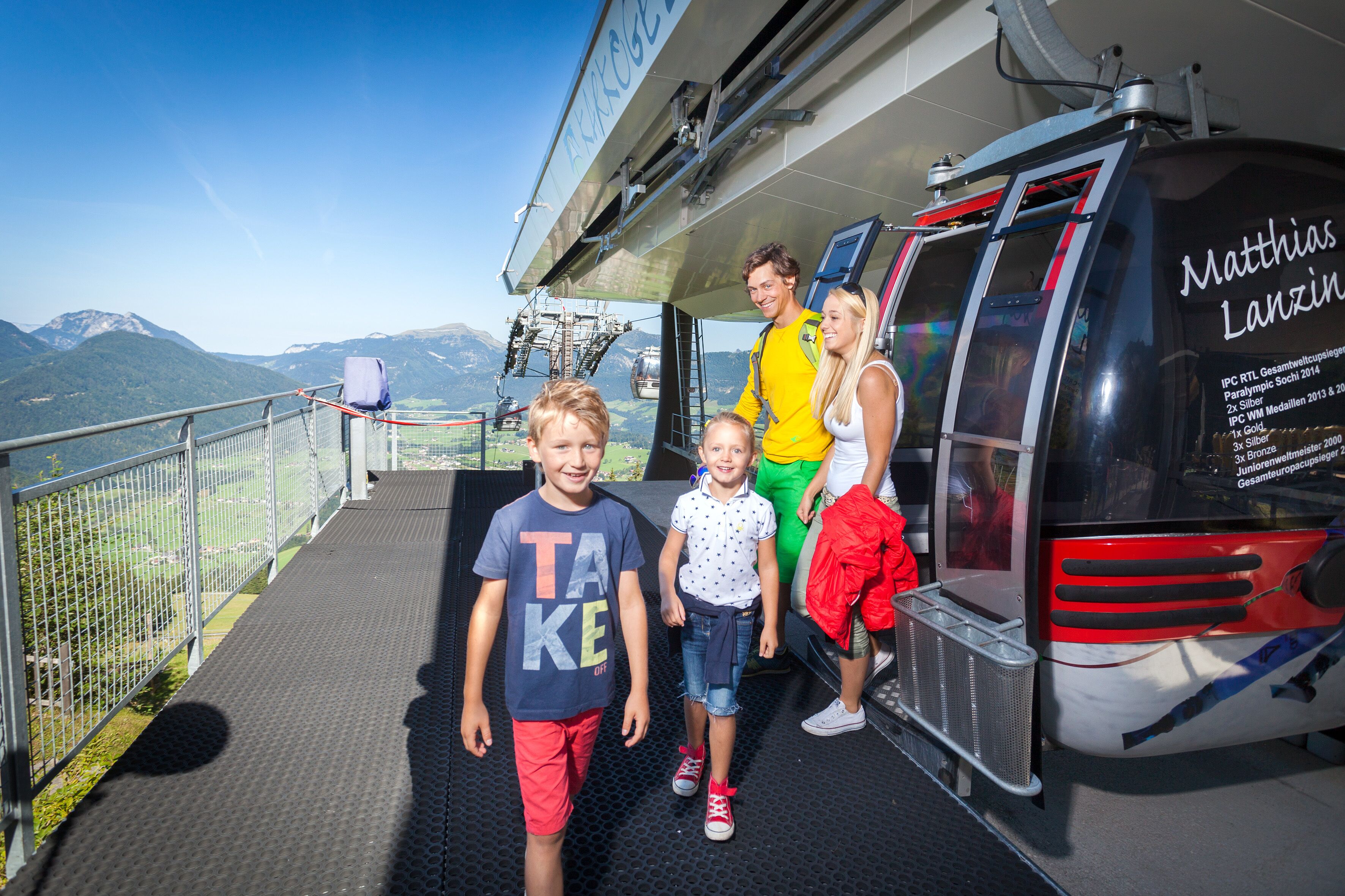 A group of people boarding a cable car with a mountainous landscape in the background.