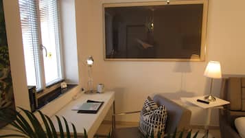Una sala de estar moderna con un escritorio blanco, un sofá, un espejo grande y una lámpara.