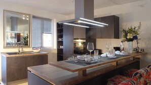 Una cocina moderna con una isla central, estanterías integradas y una zona de comedor con tapicería floral.