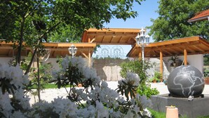 Un jardín con flores blancas, una escultura de un globo terráqueo y pérgolas de madera.