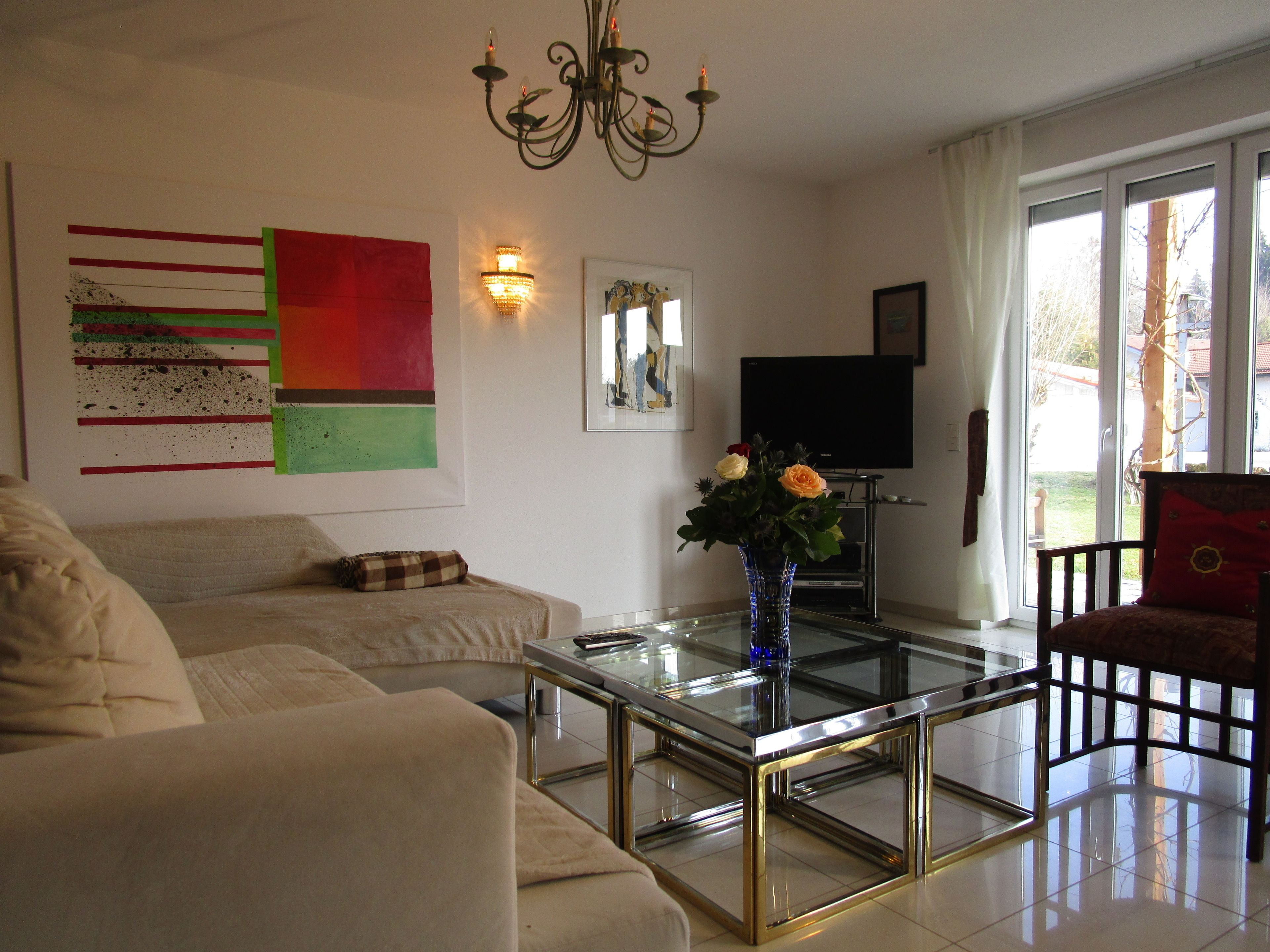 A living room with a sofa, a glass coffee table, a TV, and a window with curtains.