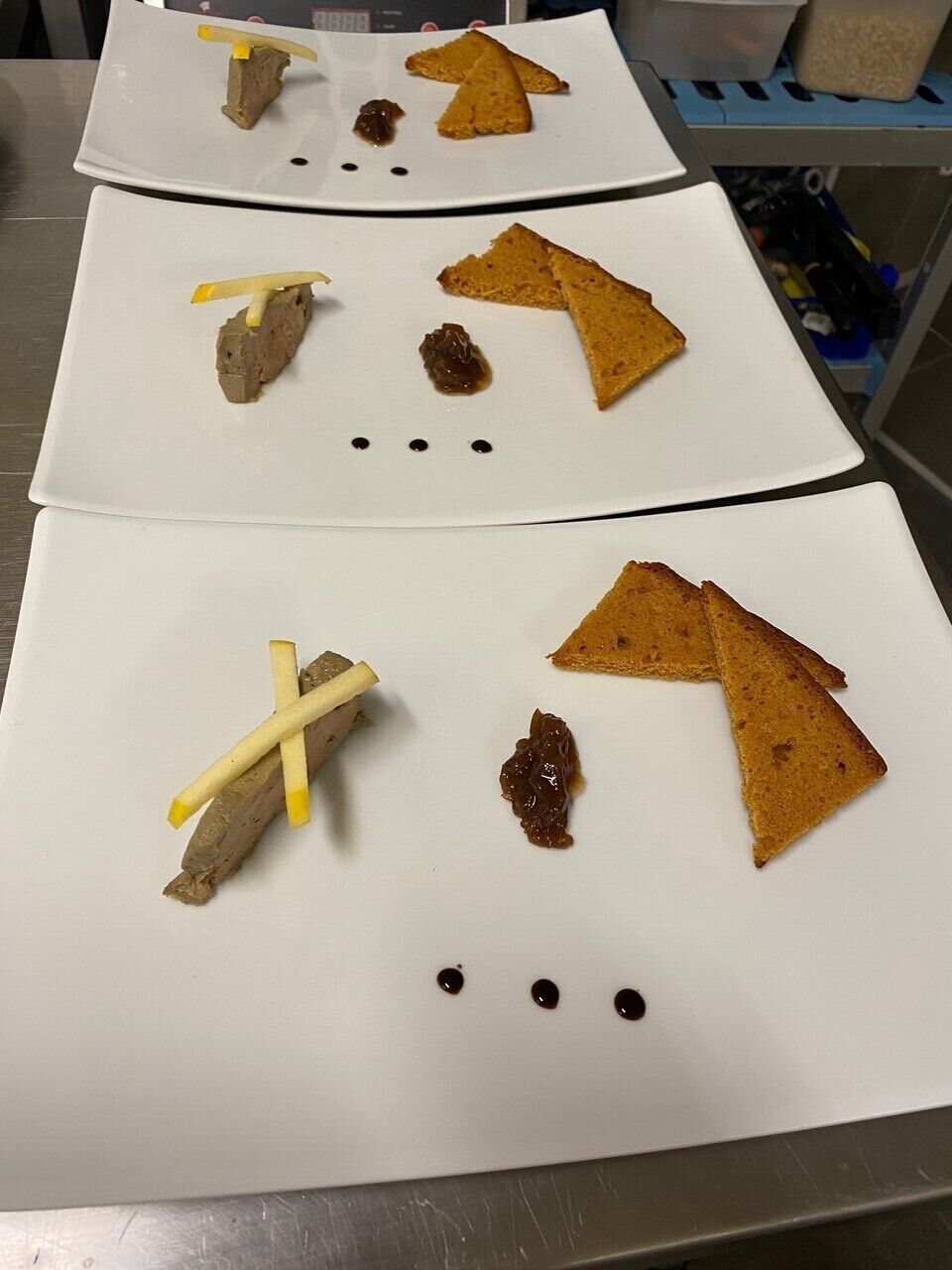 A kitchen counter with three white plates, each with triangular food items and some yellow sticks.