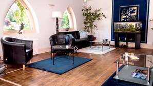 A modern living room with a black leather sofa, a glass coffee table, and a fish tank. - Le Saint Eloi (Solignac)