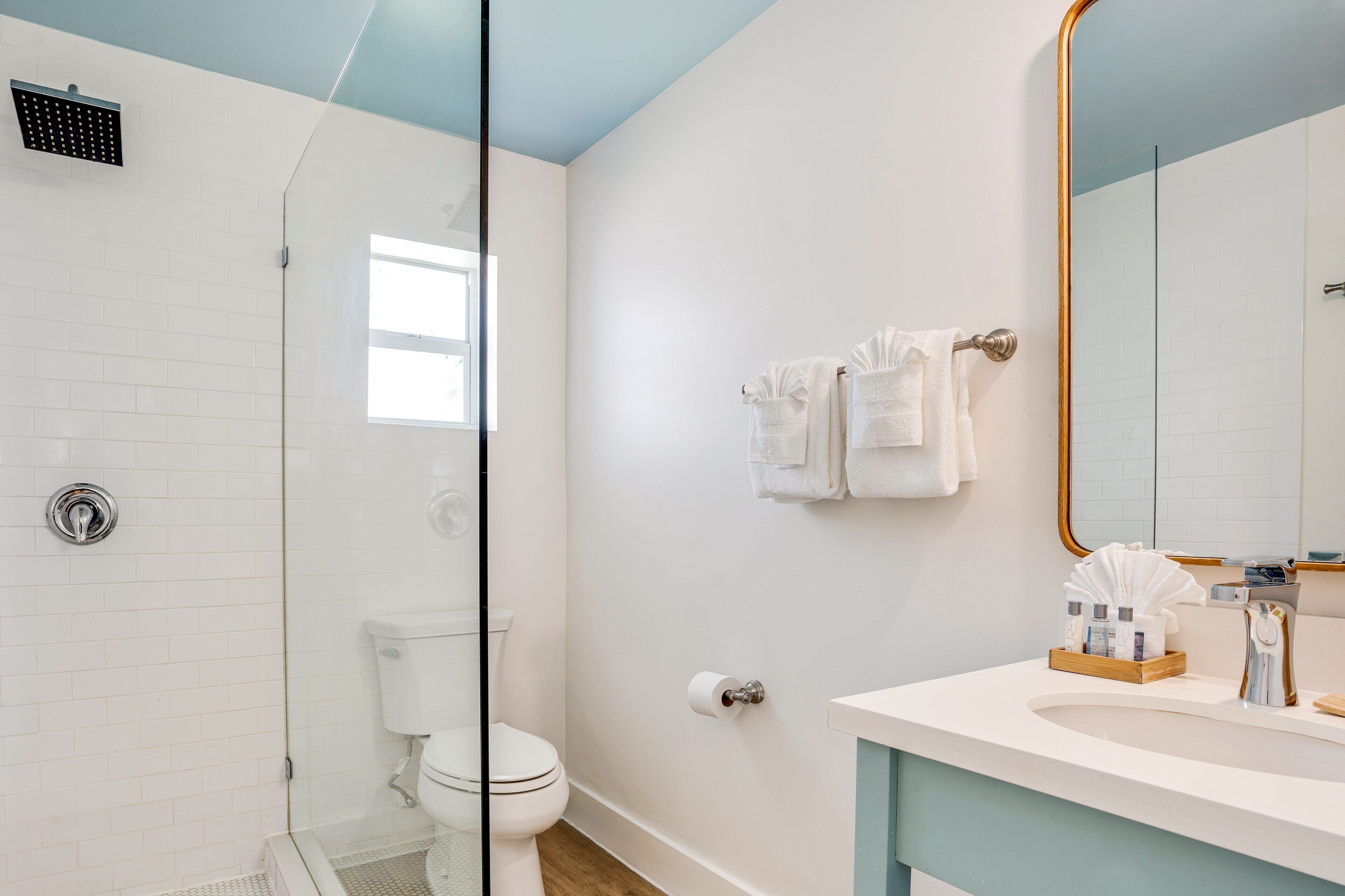 Une salle de bain moderne dotée d’une douche à parois de verre, de toilettes et d’un meuble-lavabo avec un miroir.