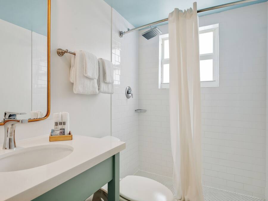 A bathroom with a white sink, a mirror, and a shower with a white curtain.