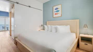 A bedroom with a large bed, two bedside tables, a nightstand, and a wall-mounted picture of fish.