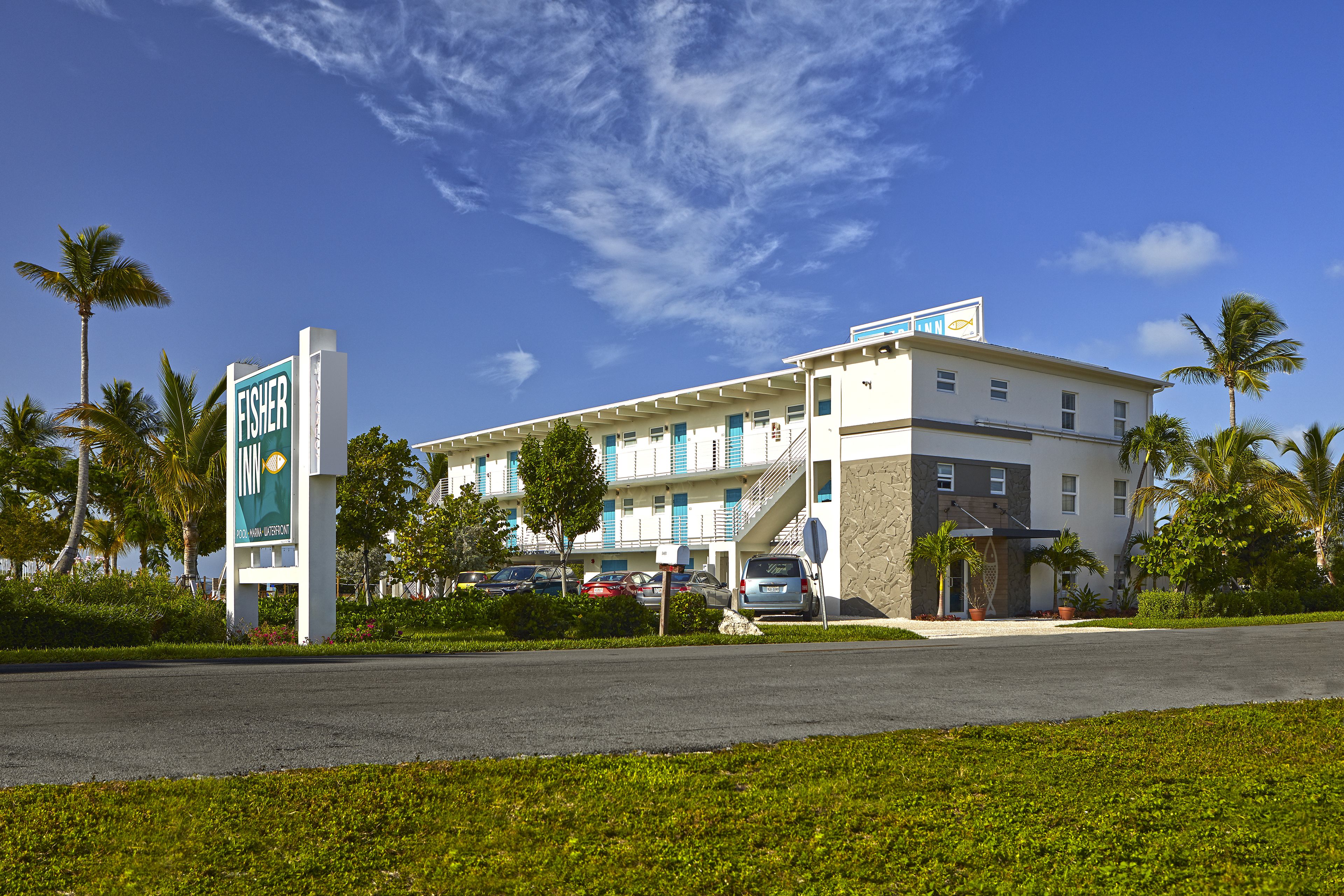 A Fisher hotel with a modern design, featuring a prominent sign, multiple floors, and a parking area.