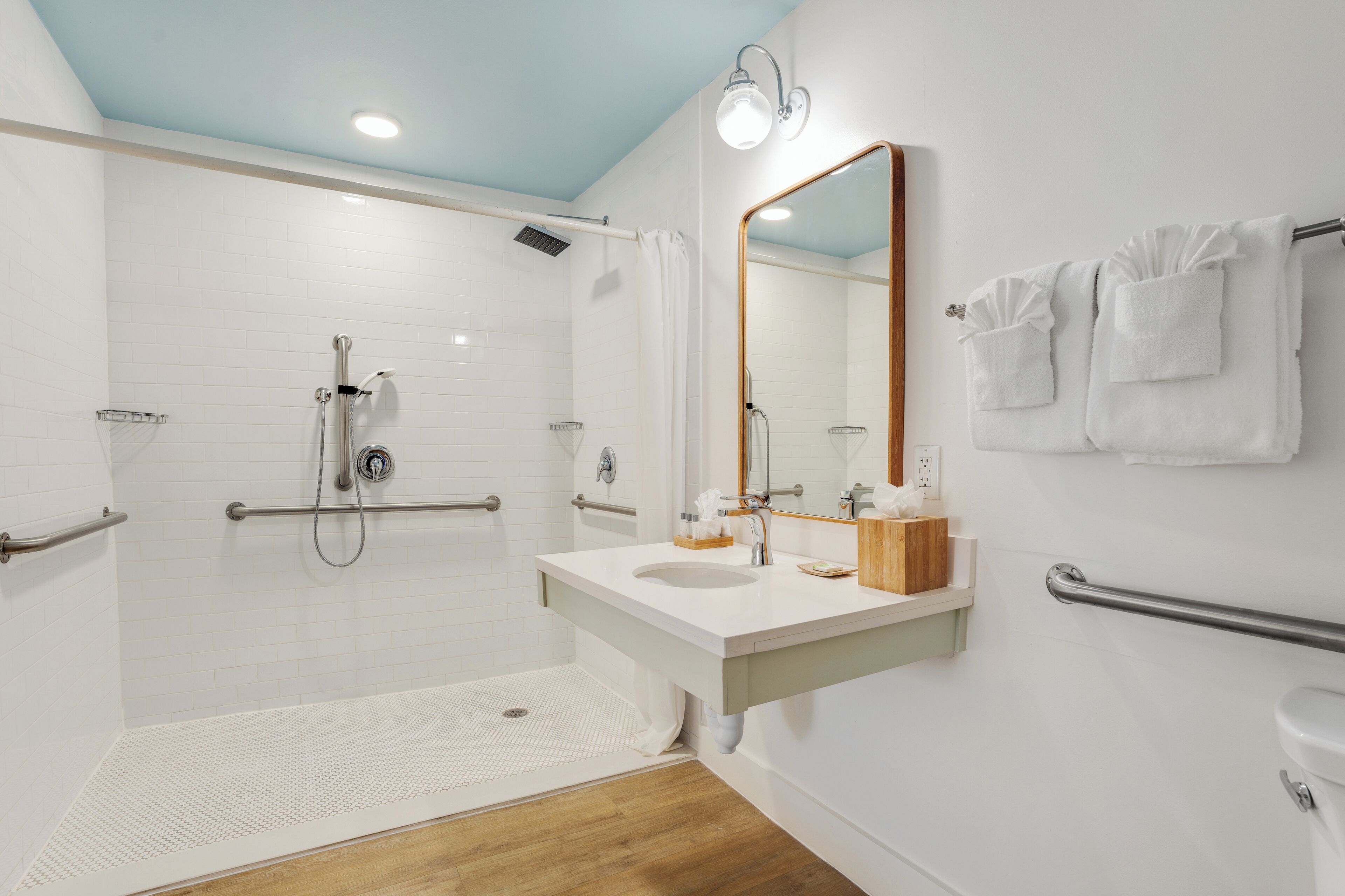 Een moderne badkamer met een douche, wastafel, spiegel en toilet.