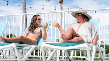 Una piscina al aire libre, sombrillas, sillones reclinables de piscina