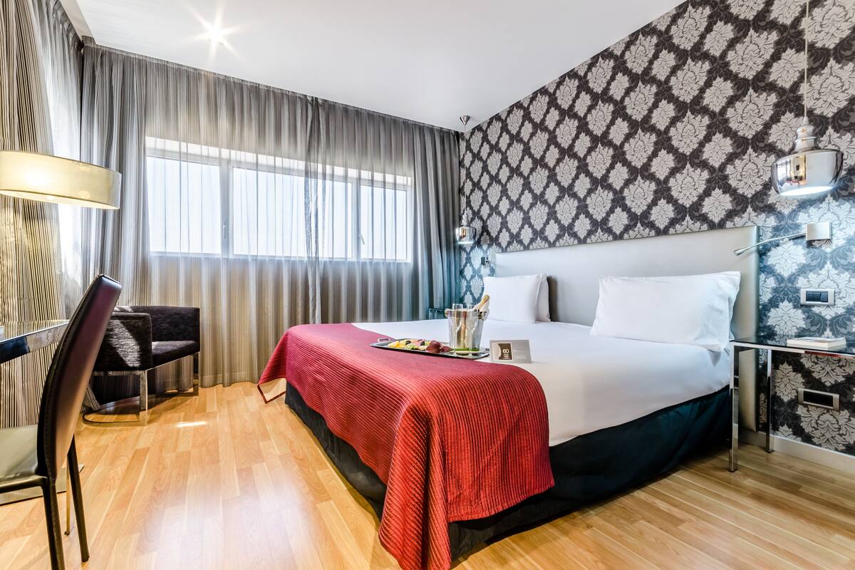 A hotel room with a large bed, a desk, and a chair.
