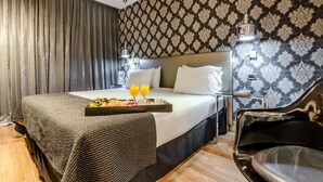 Une chambre d’hôtel avec un lit, un plateau de petit-déjeuner, une chaise et un papier peint à motifs.