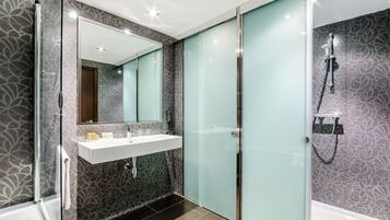Une salle de bain moderne avec une douche à parois de verre, un meuble-lavabo avec un miroir et des carreaux décoratifs.