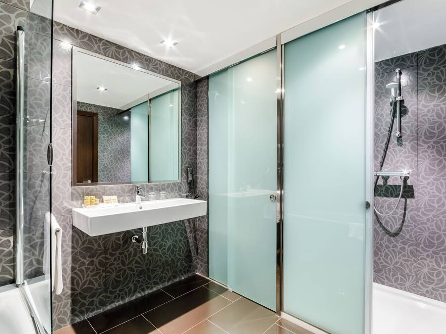 Une salle de bain moderne avec une douche à parois de verre, un meuble-lavabo avec un miroir et des carreaux décoratifs.