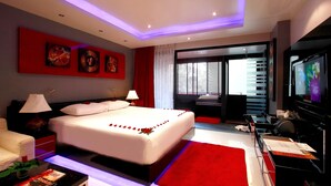 Ein modernes Hotelzimmer mit einem großen Bett, einem Fernseher, einem Schreibtisch und einem roten Teppich.