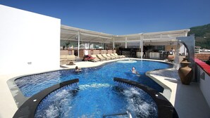 Ein Poolbereich mit mehreren Wasserspielen, Liegestühlen und einer überdachten Sitzgelegenheit.