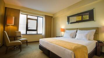 Una habitación de hotel con una cama grande, una silla, un escritorio y una ventana.
