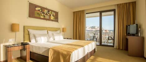 Habitación de hotel con una cama grande, un escritorio con teléfono, televisión y vistas a la ciudad desde la ventana.