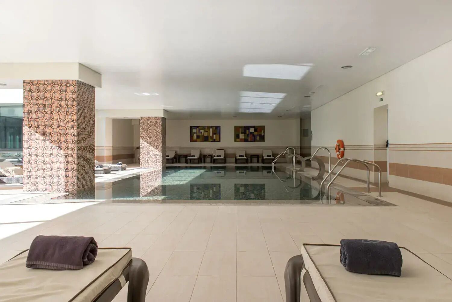 Eine Hotelhalle mit Pool, Sitzgelegenheiten und einer Rezeption.