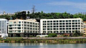 A modern hotel with multiple floors, large windows, and a view of a body of water.